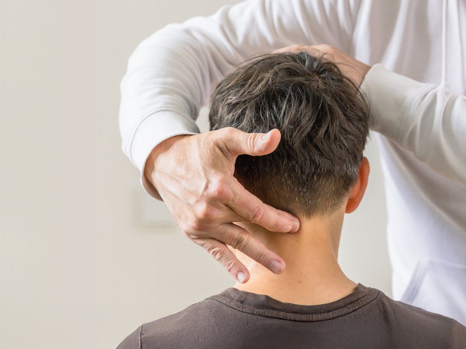 Close-up einer chirotherapeutischen Behandlung im Nacken- und Halsbereich einer Patientin.